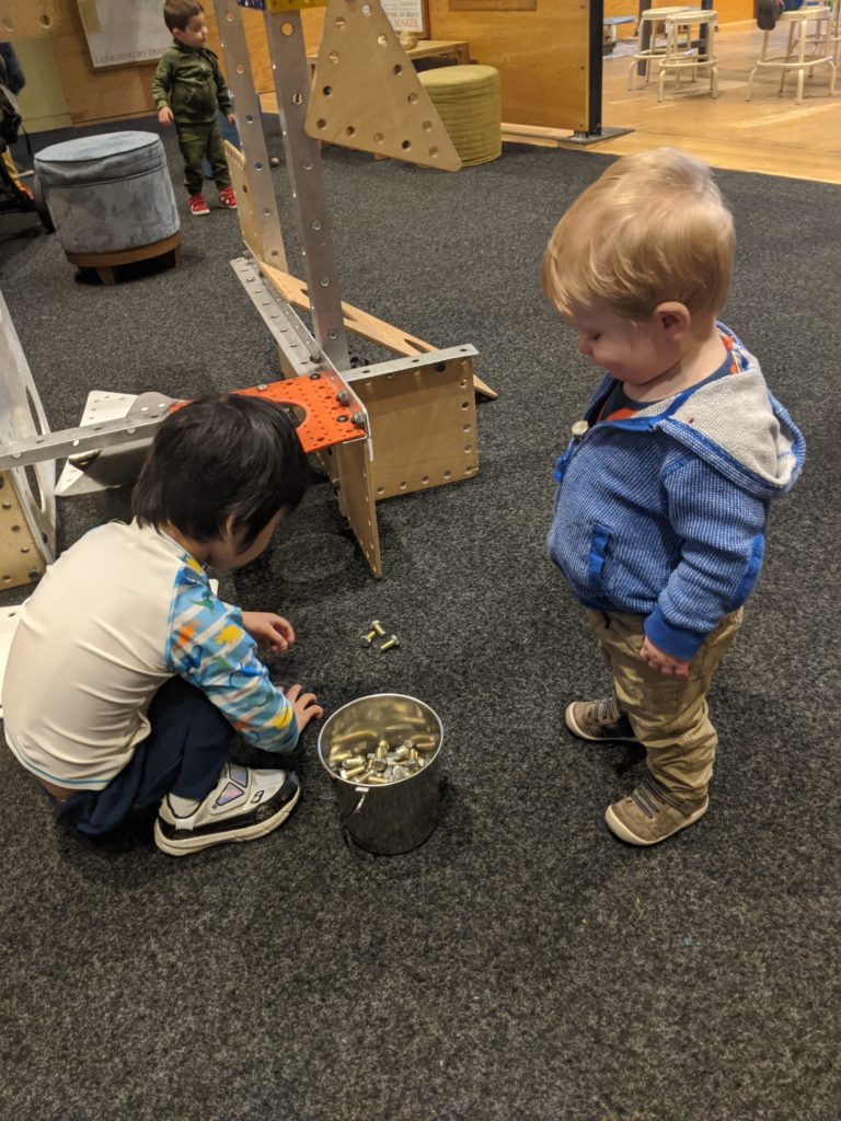 Standing by and squatting baby facing each other