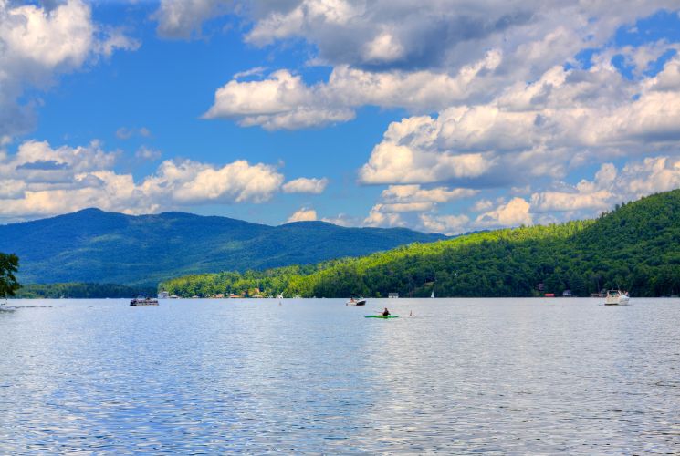 A large lake surrounded by lush green rolling hills with blue skies overhead