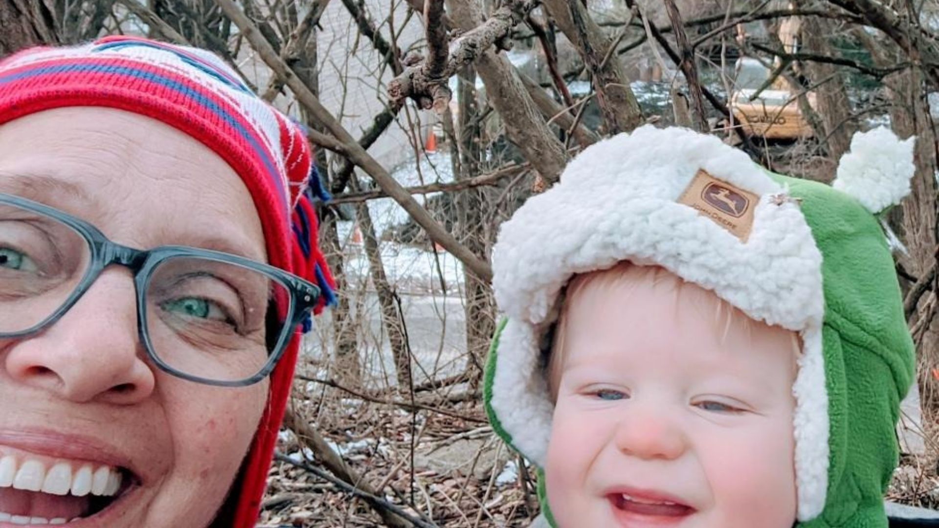 A woman and a young boy outdoors wearing colorful snow hats