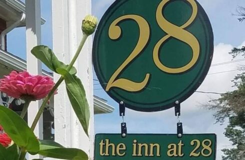 Large green circular sign with a gold number 28 hanging outside a home