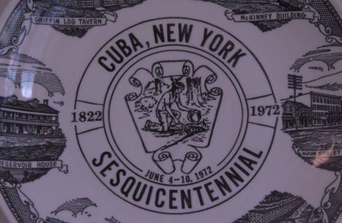 White and black decorative plate with different artist renderings of various buildings