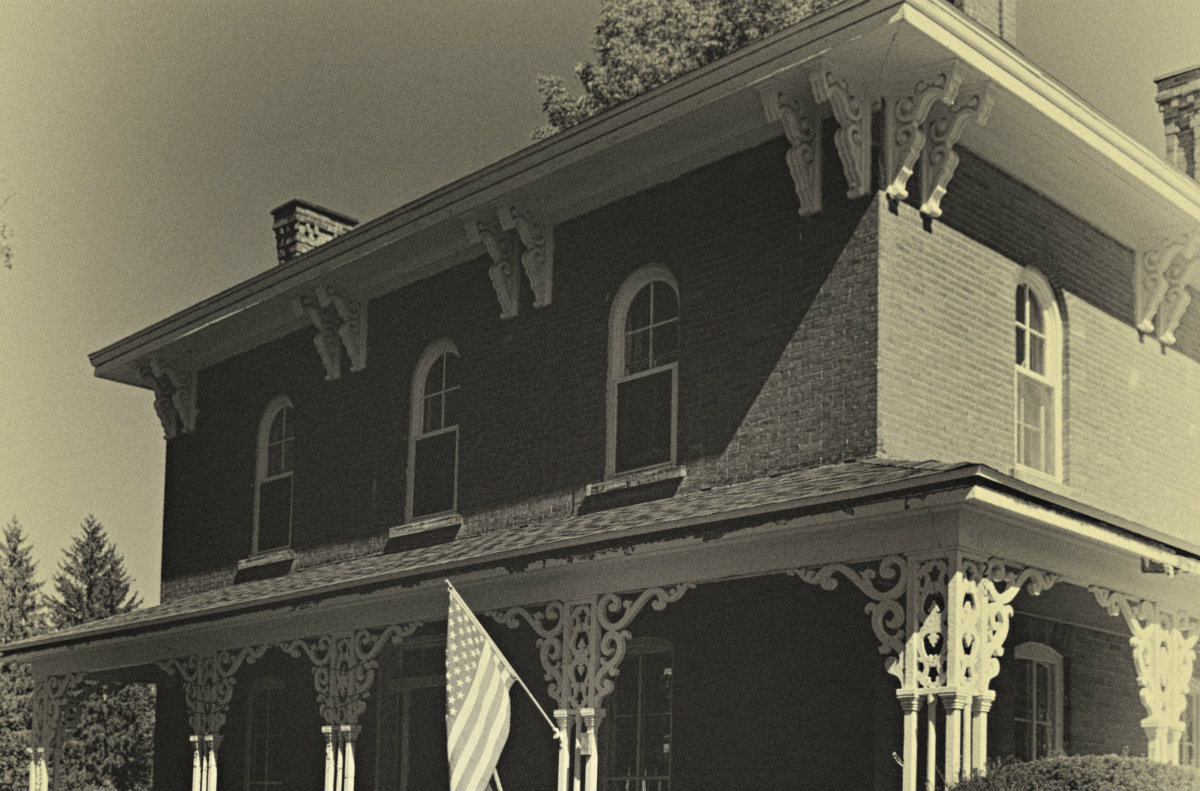 Old, faded view of historic, detailed brick home in black and white