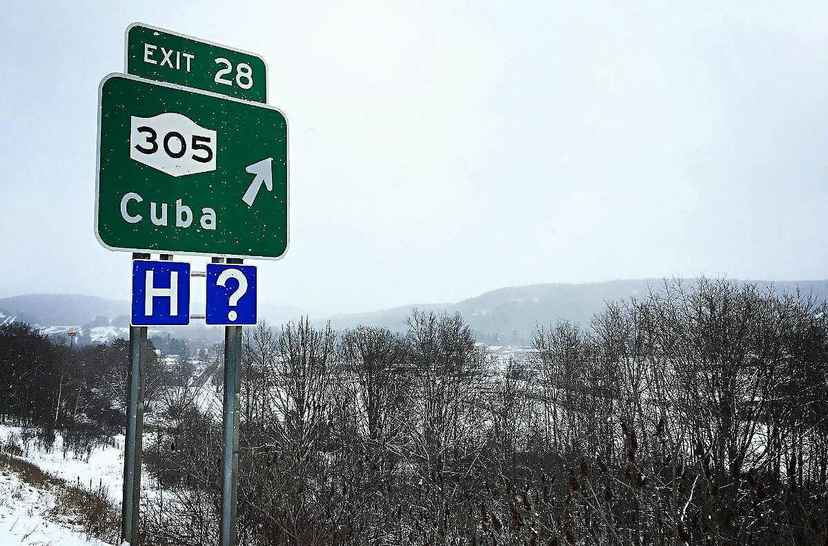 Green, highway exit twenty-eight sign with three zero five Cuba with smaller, blue H and question mark signs