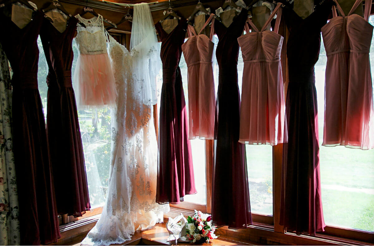 White wedding dress, six long burgundy dresses, three short pink dresses plus a pink and white dress hanging in windows