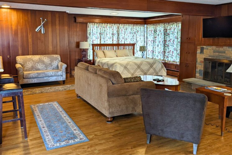 Spacious bedroom suite with bed, couches, sitting chairs, fireplace and bar area