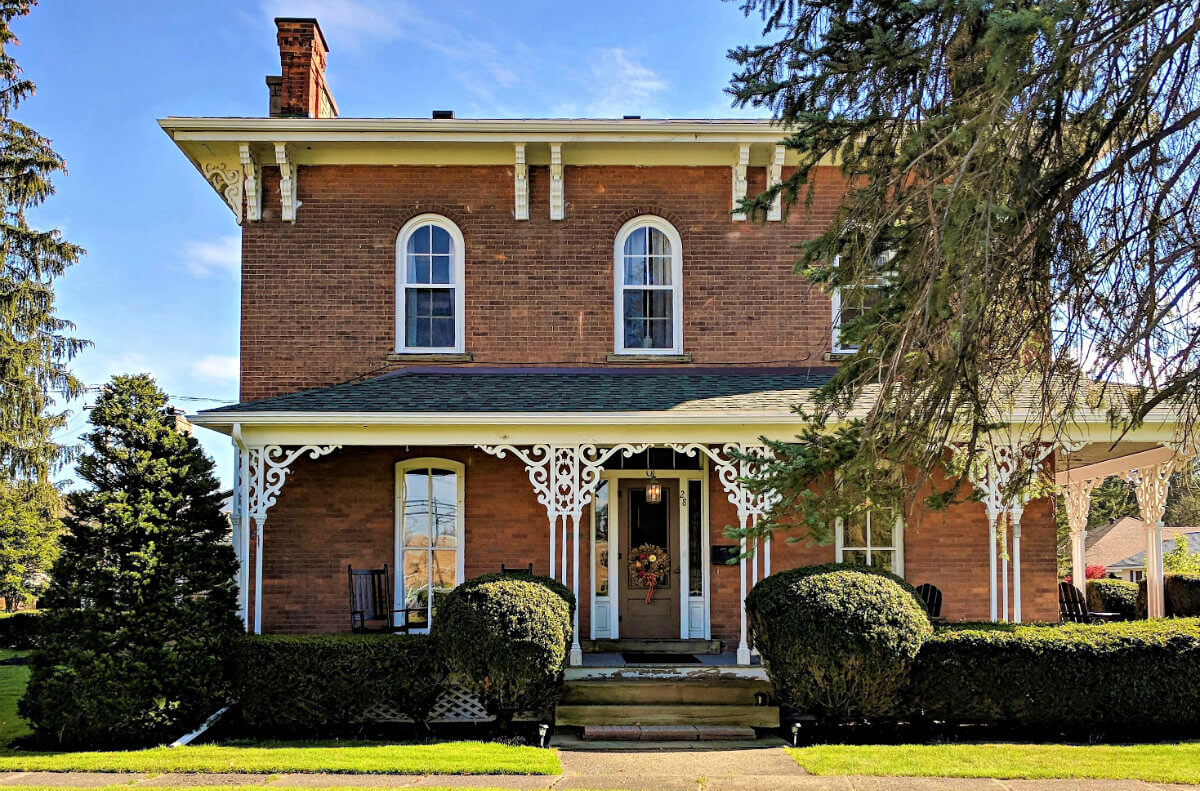 Red brick building with white trim in setting of blue sky, green grass and trees