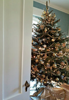 White door open showing a Christmas tree with silver, gold and white ornaments a bead garland