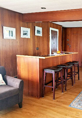 Room with brown paneled walls, brown bar and black bar stools