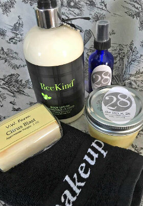 Black makeup washcloth, bar of soap, bottle of body lotion, small jar and blue spray bottle