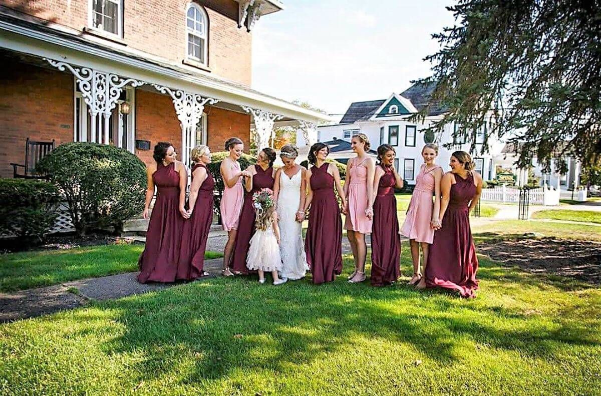 Bride and little girl with white dresses on and bridal party ladies in pink and burgundy dresses
