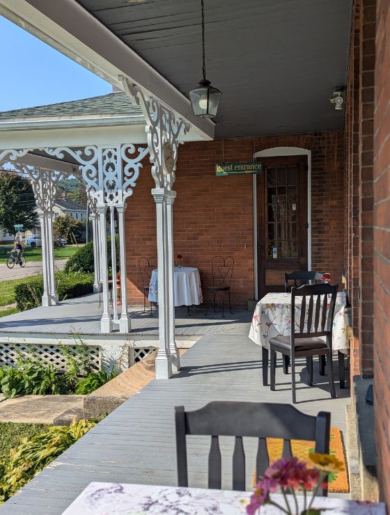 Outdoor wrap around porch with three tables for two with floral tablecloths